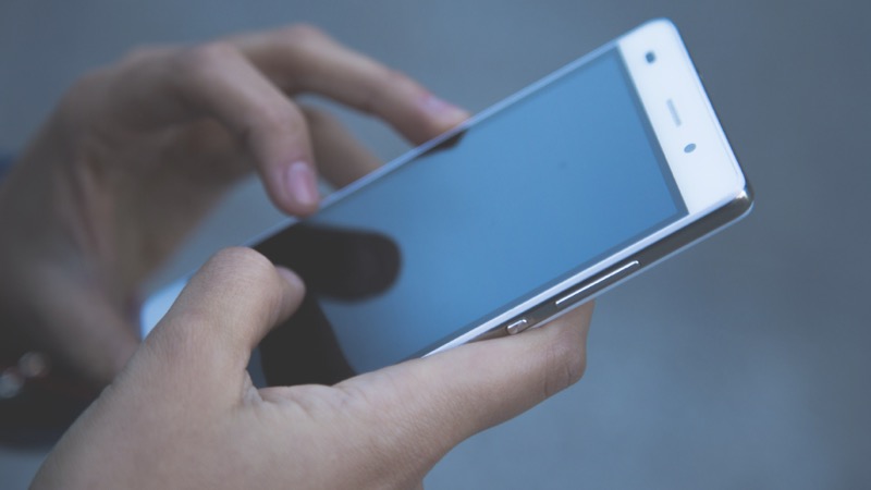 A person using a smartphone held in both hands